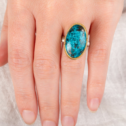 Hand wearing a turquoise ring with gold bezel and sterling silver band