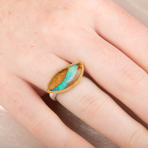 Ring with an opal stone, gold setting and silver band on a hand