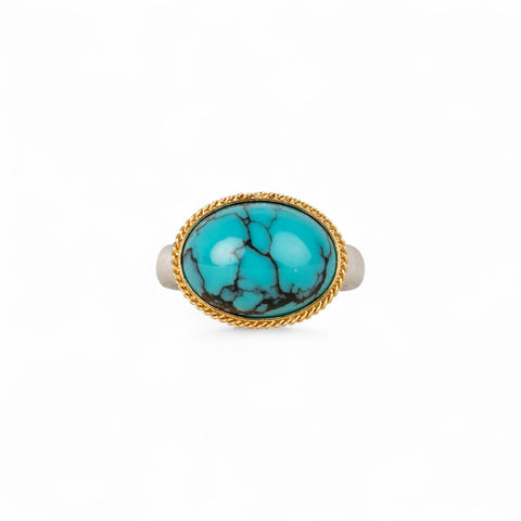 Turquoise ring with gold bezel and sterling silver band on white background