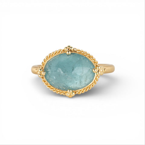 Gold ring with an aquamarine gemstone on a white background