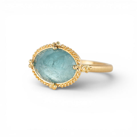 Gold ring with an aquamarine gemstone on a white background