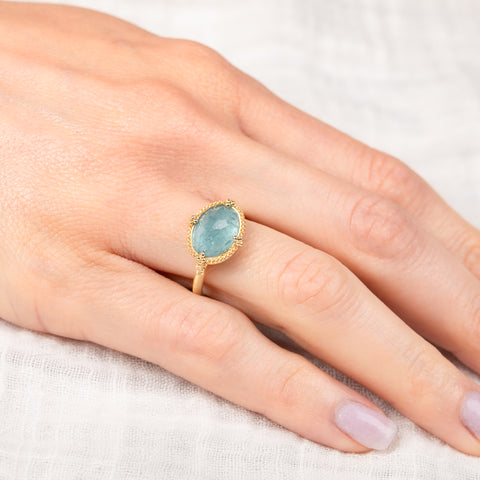 Gold ring with an aquamarine gemstone on a hand
