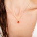 Gold necklace with a fire opal pendant on a person's neck