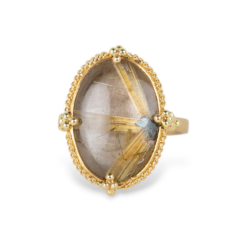 Gold ring with an oval rutilated quartz gemstone on a white background