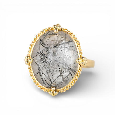 Gold ring with a tourmalated quartz stone on a white background