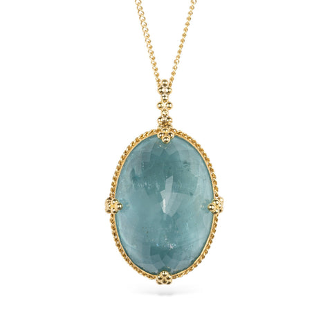 Gold necklace with an aquamarine pendant on a white background