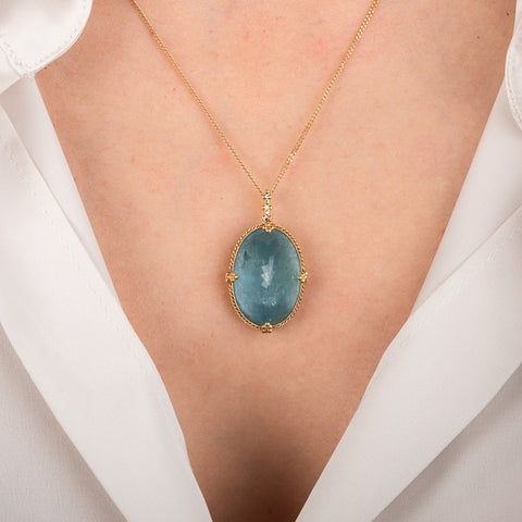 Gold necklace with an aquamarine gemstone on a person's neck
