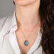 Gold necklace with an aquamarine gemstone on a person's neck