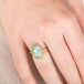 Gold ring with an Ethiopian opal stone on a person's hand