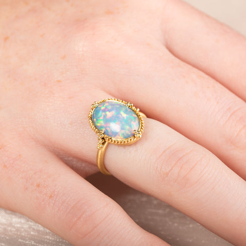 Gold ring with an Ethiopian opal stone on a person's hand