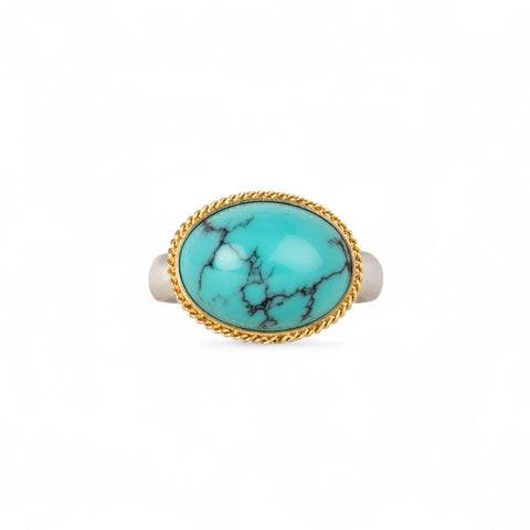 Turquoise ring with gold bezel and sterling silver band on white background