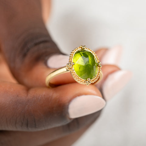 Gold ring with a peridot gemstone held in hand