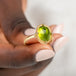 Gold ring with a peridot gemstone held in hand