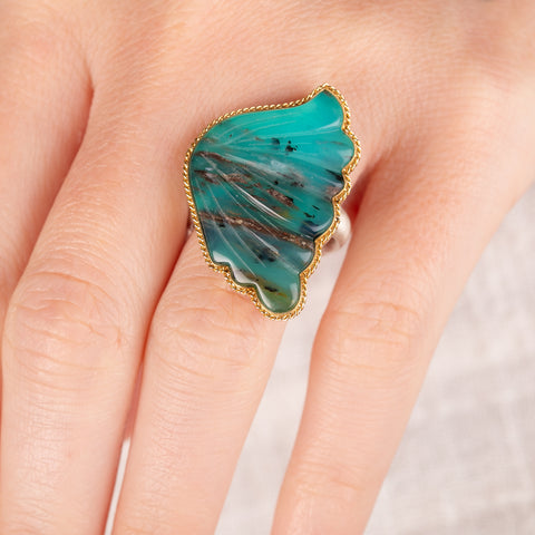 Hand wearing a peruvian opal wing ring with gold bezel and silver band