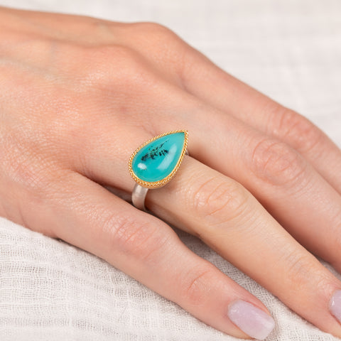 Handmade ring with peruvian opal stone on a hand against a neutral background