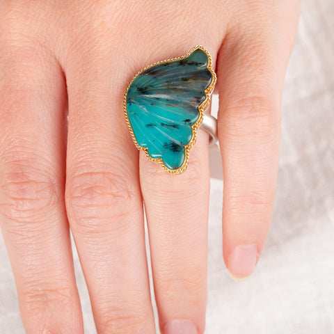 Hand wearing a Peruvian Opal wing ring with gold bezel and silver band