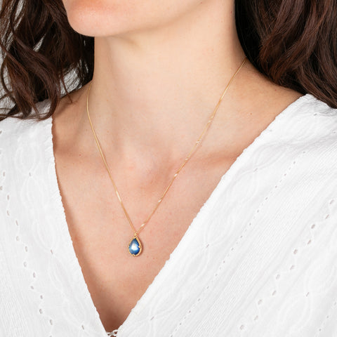 Necklace with a moonstone pendant worn by a person in a white top