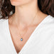 Necklace with a moonstone pendant worn by a person in a white top