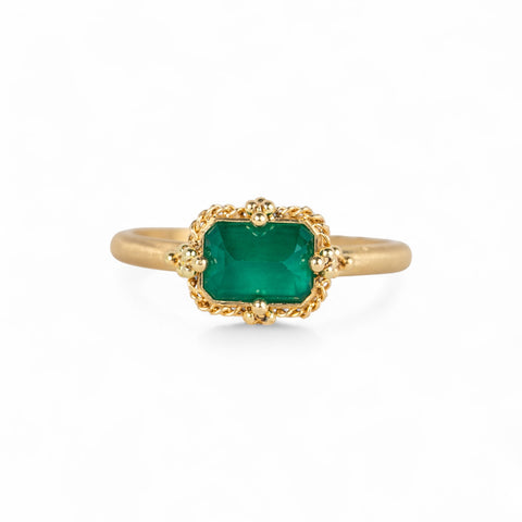 Gold ring with an emerald gemstone on a white background