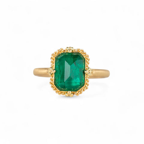 Gold ring with an emerald gemstone on a white background