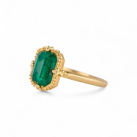 Gold ring with an emerald gemstone on a white background