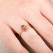 Gold ring with a watermelon tourmaline gemstone worn on a persons finger