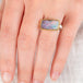 Hand wearing a boulder opal ring with gold bezel with a sterling silver band 