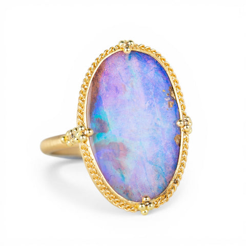 Gold ring with a boulder opal stone on a white background