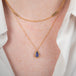 Gold necklace with a tanzanite teardrop pendant on a person