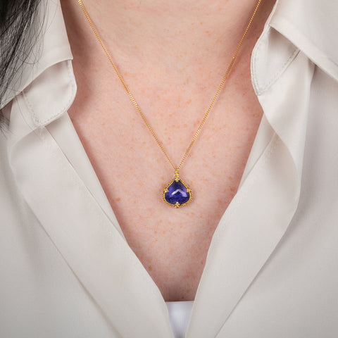Tanzanite pendant on a gold chain against a person