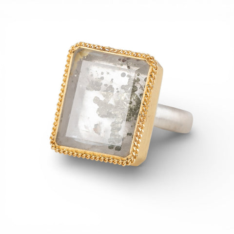Ring with a gold frame, silver band and quartz with pyrite stone on a white background