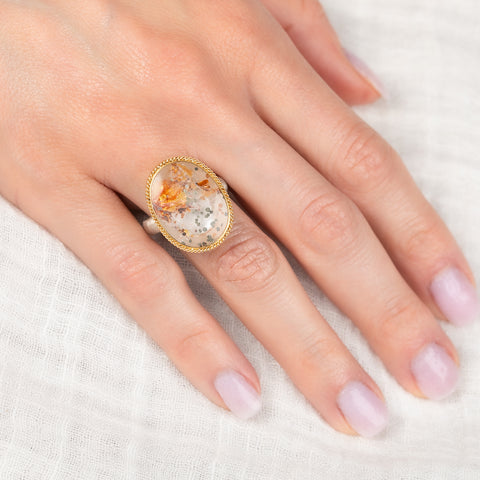 Ring with a gold bezel, silver band and quartz with pyrite stone on a hand on a white background