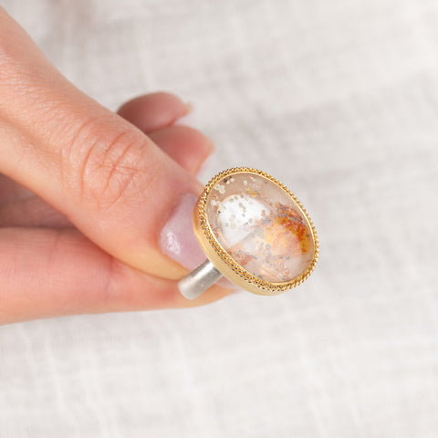 Ring with a gold bezel, silver band and quartz with pyrite stone held in hand