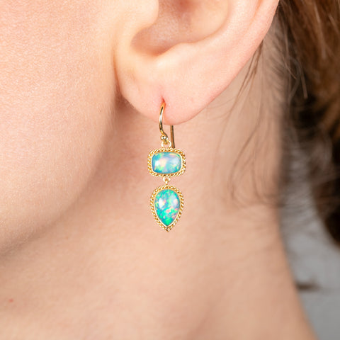 Gold earrings with Ethiopian opal worn by a person