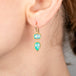 Gold earrings with Ethiopian opal worn by a person
