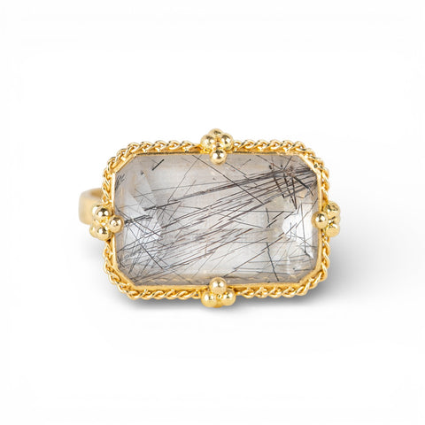 Gold ring with a tourmalated quartz stone on a white background