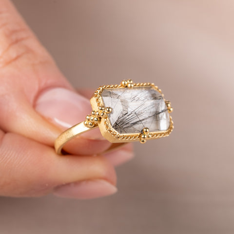 Gold ring with a tourmalated quartz stone held in hand