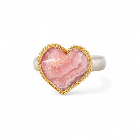 Heart-shaped ring with rhodochrosite stone, gold setting and silver band on a white background