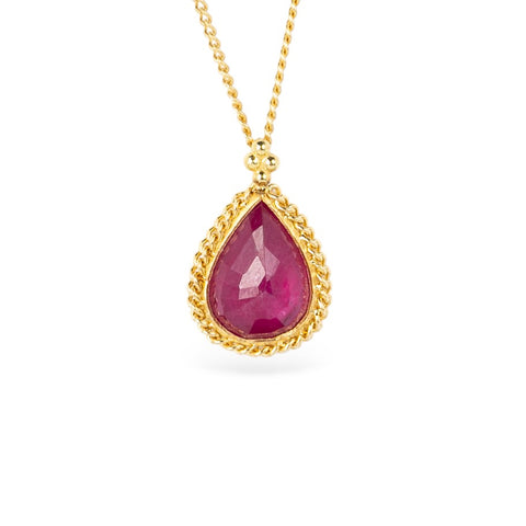 Gold necklace with a teardrop-shaped ruby pendant on a white background