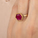 Gold ring with a hexagonal ruby gemstone on a person's finger