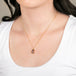 Gold necklace featuring a ruby gemstone on a person