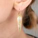 Gold earring with a rutilated quartz gemstone worn by a person