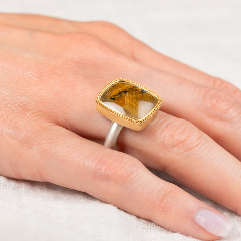 Gold and silver ring with a rutilated quartz stone on a hand