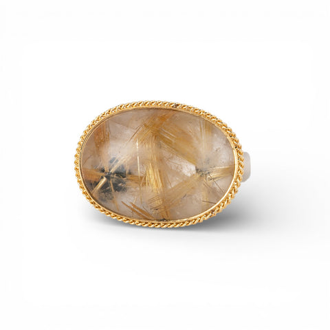 Ring with a gold bezel, silver band and rutilated quartz stone on a white background