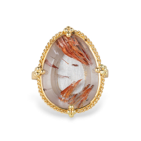 Gold ring with a rutilated topaz stone on a white background
