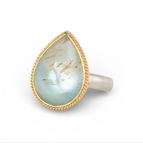 Teardrop-shaped gold and silver ring with rutilated topaz stone on a white background