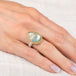 Rutilated topaz ring with a teardrop-shaped gemstone on a hand against a white background