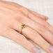 Gold ring with a brown diamond on a hand against a neutral background
