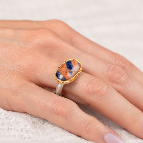 Gold and silver ring with an oval sodalite stone on a hand