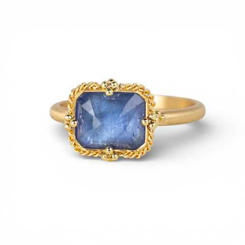 Gold ring with a blue tanzanite gemstone on a white background